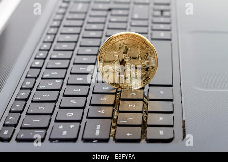 Studio shot of golden Bitcoin virtual currency on laptop. Close-up of front side. Stock Photo