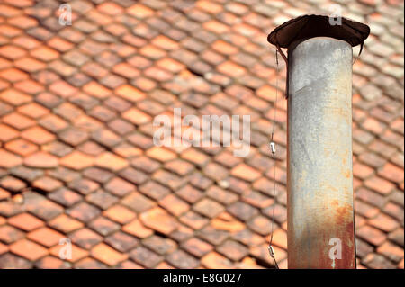 Architecture detail with rusty tin chimney and tile roof on the background Stock Photo