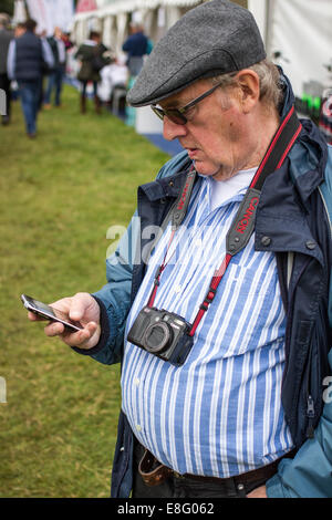 Pensioner in a flat cap using smart phone in England UK Stock Photo