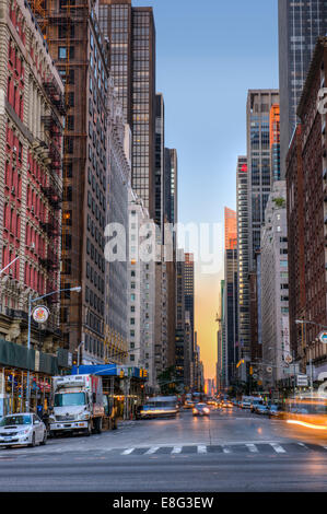 Early morning traffic on the Avenue of the Americas as the sun rises over lower Manhattan in the distance. Stock Photo