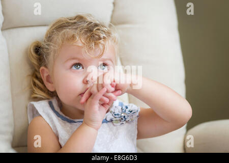 Scared Blonde Haired and Blue Eyed Little Girl Sitting in Chair. Stock Photo