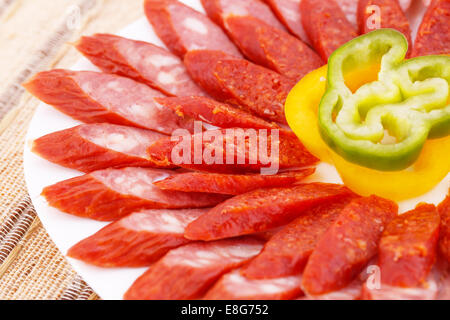 Fresh sausages and peppers in plate on bamboo mat background. Stock Photo