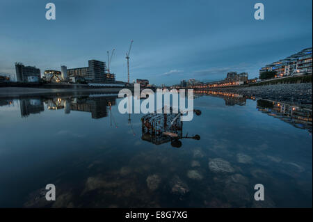 A dumped supermarket trolley under a bridge in the River Thames at low tide Stock Photo
