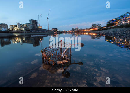A dumped supermarket trolley under a bridge in the River Thames at low tide Stock Photo