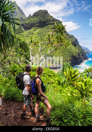Hikers on the Kalalau Trail on Kauai, with glimpse of Hanakapiai Beach Stock Photo