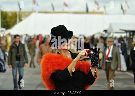 Lady wearing vintage fashions taking a picture with a point-and-shoot camera at the Goodwood Revival Stock Photo
