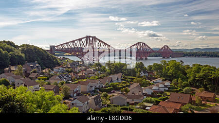 Iconic 19th century cantilever bridge over Firth of Forth with houses of riverbank town of Queenstown in foreground Scotland Stock Photo