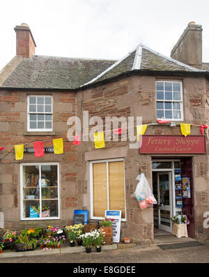 Small old fashioned general store with pots of colourful plants on footpath in village of Fettercairn in Scotland Stock Photo