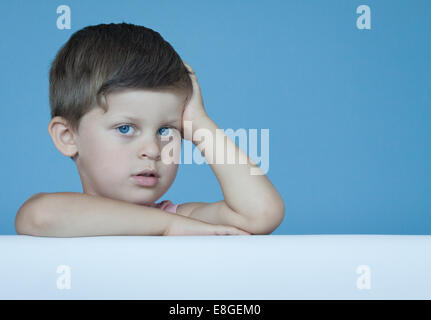 Three years old cute smart boy express positive emotions posing over blue wall background Stock Photo