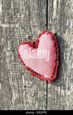 Pink handmade heart decoration with ornamental pattern outside hang by needle on wooden board background Stock Photo