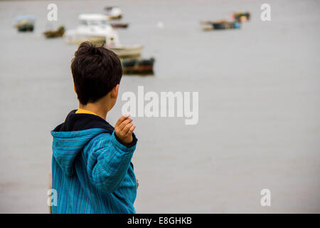 Spain, Madrid, Boy playing with stones in sea Stock Photo