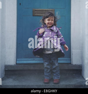 Smiling windswept girl standing on a doorstep, London, England, UK Stock Photo