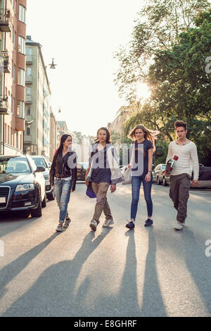 Full length of confident high school students walking on city street Stock Photo