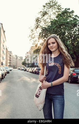 Portrait confident female high school student standing on city street Stock Photo