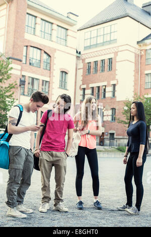 Full length of male and female students standing on high school schoolyard Stock Photo