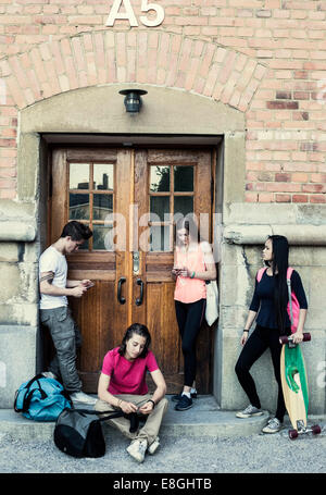 Full length of students waiting outside entrance of high school building Stock Photo