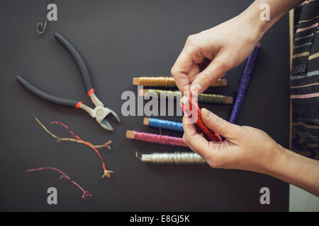 Directly above shot of woman rolling wire on spool at table Stock Photo