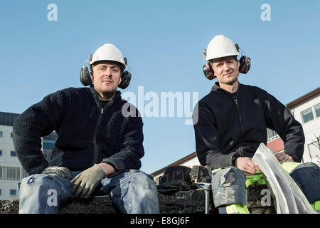 Portrait of confident workers at construction site against clear blue sky Stock Photo