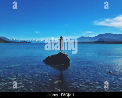 Woman standing on a rock, Lake Tekapo, Canterbury, New Zealand Stock Photo