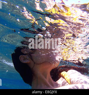 Close-up of a woman in a dress swimming underwater, Sounion, Lavreotiki, Greece Stock Photo