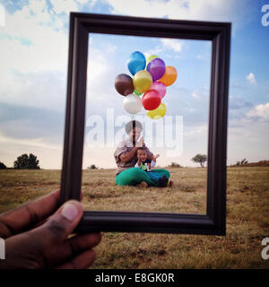 Man holding a Picture frame in front of a Mother and son in a meadow, Roodeport, Johannesburg, Gauteng, South Africa Stock Photo