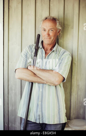 Portrait of confident man with shovel standing arms crossed against wall Stock Photo