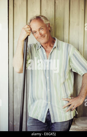 Portrait of smiling man with shovel standing against wall Stock Photo