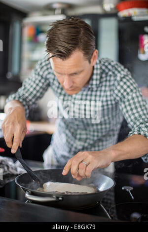 Man cooking fish in kitchen Stock Photo