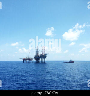 Oil and gas platform with offshore vessel transporting cargo Stock Photo