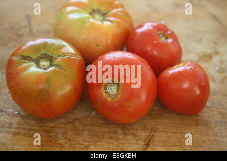 Five Heirloom Tomatoes on wooden chopping board Stock Photo