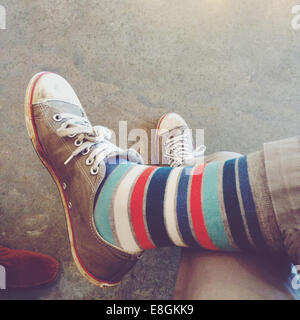 Close-up of a person wearing striped socks and trainers Stock Photo