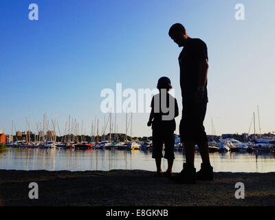 Stockholm, Sweden A Boy And His Father Throwing Rocks Into The Water And Look At Boats Stock Photo