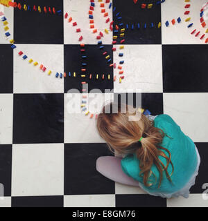 Girl sitting on the floor setting up lines of dominos Stock Photo