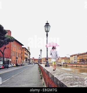 Girl walking along a wall in the rain, Pisa, Tuscany, Italy Stock Photo