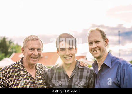 Portrait of three generations male family smiling against sky Stock Photo