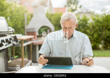 Senior man using digital tablet at table in yard Stock Photo