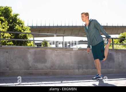 Full length of man doing stretching exercise on bridge Stock Photo