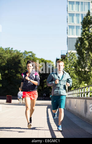 Full length of multi-ethnic couple jogging on bridge Stock Photo