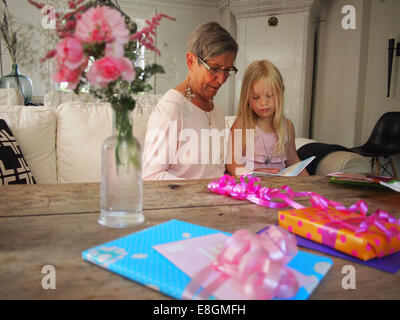 Grandmother reading a book with her granddaughter on her birthday, Sweden Stock Photo