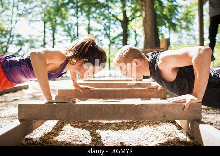 Side view of couple doing push-ups at outdoor gym Stock Photo