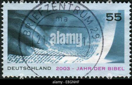 GERMANY - CIRCA 2003: Postage stamp printed in Germany, dedicated to the Bible Year, shows a hand and an open Bible, circa 2003 Stock Photo