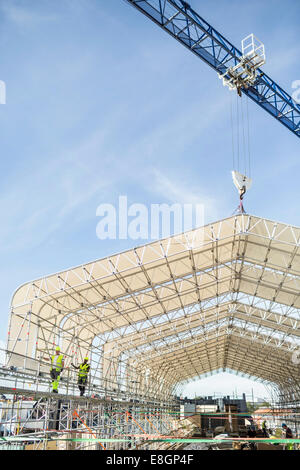 Workers working at construction site against sky Stock Photo