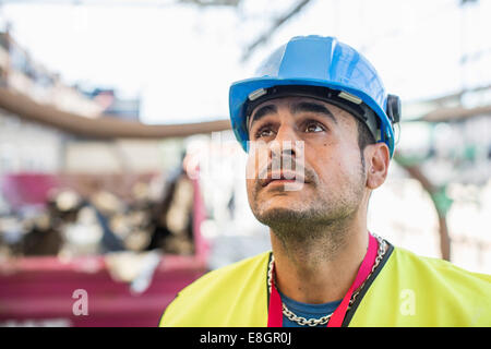 Worker looking up at construction site Stock Photo