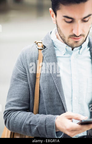 Businessman text messaging through smart phone outdoors Stock Photo