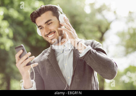 Happy businessman listening music though smart phone outdoors Stock Photo