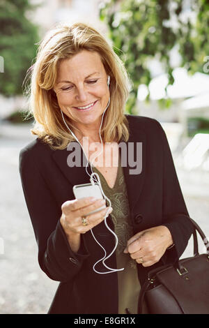 Happy businesswoman listening music through smart phone outdoors Stock Photo