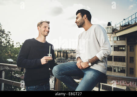 Happy male friends communicating on roof garden Stock Photo