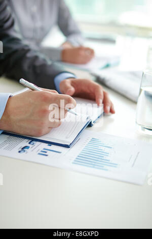 Man putting something down in his notebook Stock Photo
