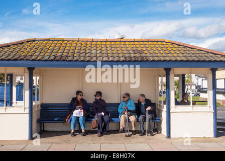 Four pensioners, 3 females and 1 male sitting on the promenade at Teignmouth in Devon. Stock Photo