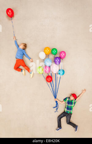 Children flying away on balloons Stock Photo